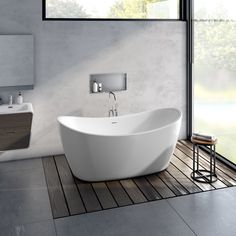 a large white bath tub sitting on top of a wooden floor next to a window