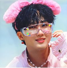 a young man wearing glasses and a pink bunny ears hat with beads on his head