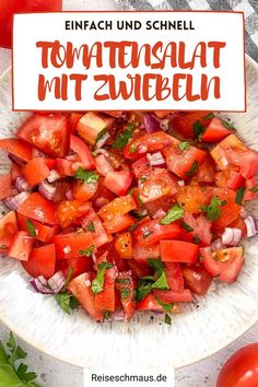 a white bowl filled with tomatoes and onions on top of a table next to fresh herbs