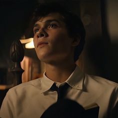 a young man wearing a white shirt and black tie in a dark room with lights on