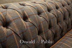 an upholstered couch with brown and blue checkered fabric on the armrests