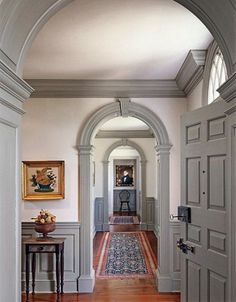 an archway leads into a hallway with hardwood floors