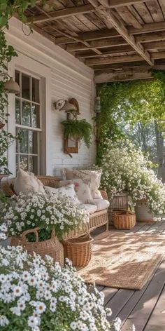 a porch covered in lots of white flowers and greenery next to a wooden bench