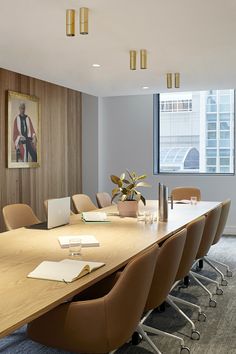 an office conference room with large wooden table and brown chairs in front of a window