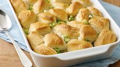 a casserole dish filled with chicken pot pies and green onions next to a spoon