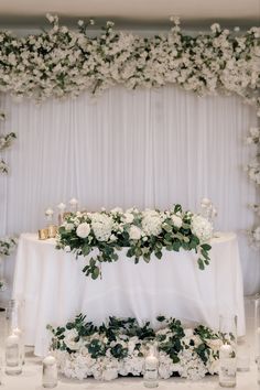 a table with white flowers and candles on it