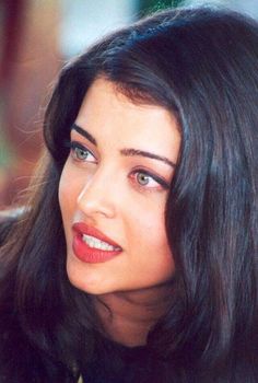 a close up of a woman with long hair wearing a black shirt and red lipstick