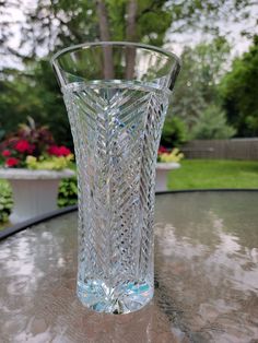 a glass vase sitting on top of a table in the middle of a garden area