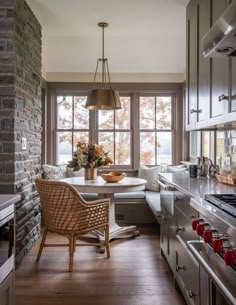 a kitchen with an oven, table and chairs next to a window in the wall