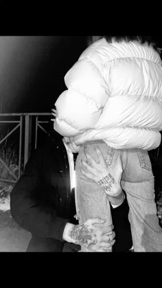 a man is holding his head down and covering him from the wind with an overstuffed coat