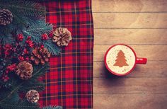 a cup of hot chocolate sitting on top of a wooden table next to pine cones