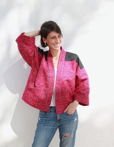 a woman standing in front of a white wall with her hands on her head and smiling