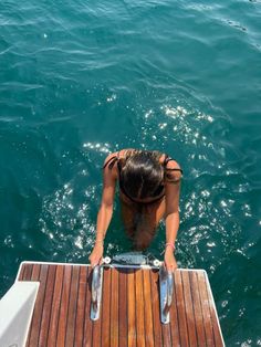 a woman standing on the edge of a boat looking down at the water from above