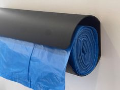 a roll of blue tarp sitting on the side of a wall next to a black tube