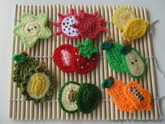 crocheted fruit and vegetable appliques are displayed on a bamboo place mat