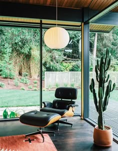 an eames chair and ottoman in the living room with large glass doors leading outside