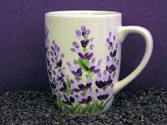 a white coffee cup with purple flowers painted on it