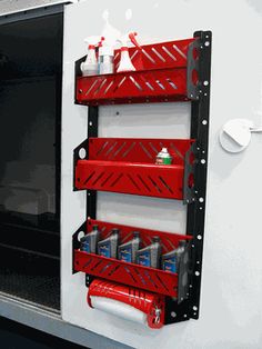 the red shelf is attached to the side of a white wall and holds various items