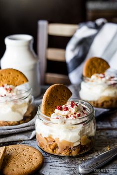 two cookies in a jar with whipped cream and graham crackers on the table next to them