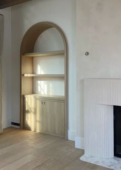 an empty living room with a fireplace and shelves