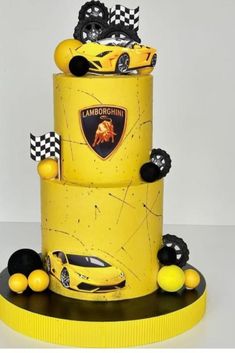 a three tiered cake with yellow and black cars on the top, in front of a white background