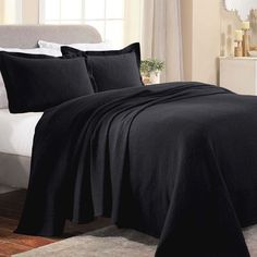 a bed with black sheets and pillows in a room