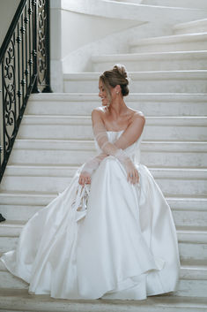 a woman in a wedding dress sitting on some stairs with her hands behind her back