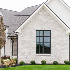 a white brick house with black windows and grass