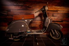 a motor scooter is parked in front of a wooden wall and tile floor