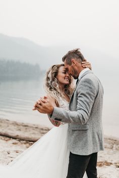 a bride and groom hugging on the beach