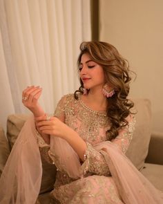 a woman sitting on top of a couch wearing a pink dress and holding something in her hand