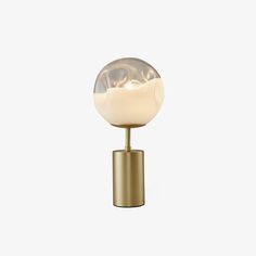 a gold table lamp with a glass ball on it's base and a white background