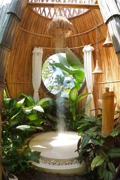 a fountain in the middle of a garden with lots of greenery and plants around it