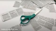 a pair of green scissors sitting on top of a pile of newspaper