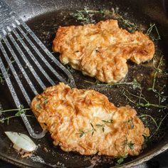 two fried meat patties in a skillet with a fork