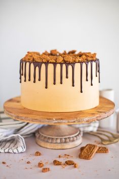 a cake with chocolate drizzle and cookies on the side sitting on a table