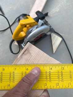 a person holding a measuring tape next to a piece of wood with a tool on it