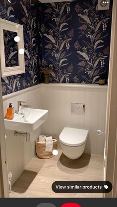 a white toilet sitting in a bathroom next to a sink and mirror on a wall