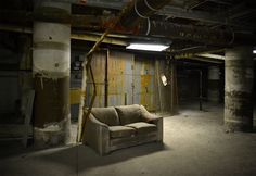 a couch sitting in the middle of a room with exposed pipes on the ceiling and walls