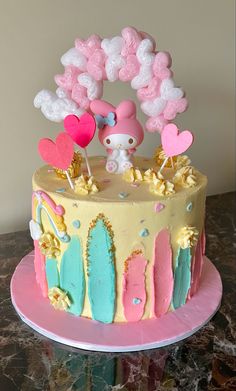 a hello kitty themed cake on a pink plate with balloons and hearts in the air