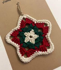 a crocheted ornament is hanging on a brown card with white and green trim