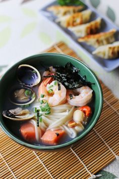 a green bowl filled with noodles and shrimp