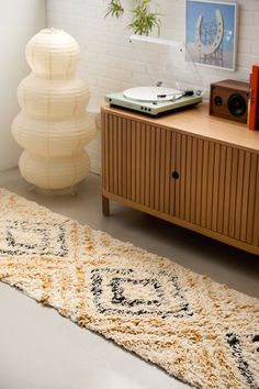 a rug on the floor in front of a wooden cabinet and record player next to it