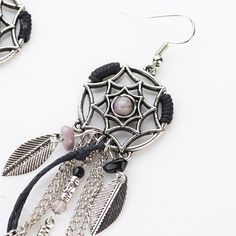 a pair of earrings with beads and feathers hanging from the earwires on a white background