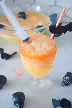 two halloween cocktails sitting on top of a table next to black candies and bats