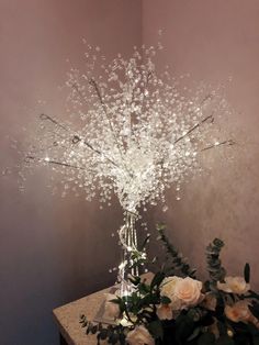 a vase filled with flowers sitting on top of a table next to a wall covered in lights