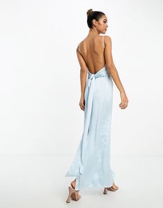 a woman wearing a blue dress with a backless top and high slits is standing in front of the camera