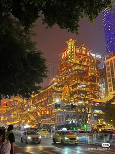 a city street filled with lots of traffic and tall buildings in the background at night