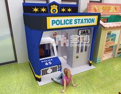 there is a police station in the playroom with two children playing inside it and one child sitting on the floor