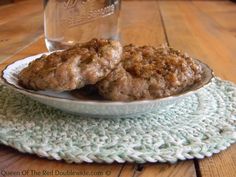 two meat patties in a bowl on a placemat next to a glass of water